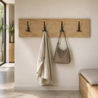 Black wall-mounted coat rack with three hooks, STAALFABRIQ brand, designed for hanging coats and accessories.