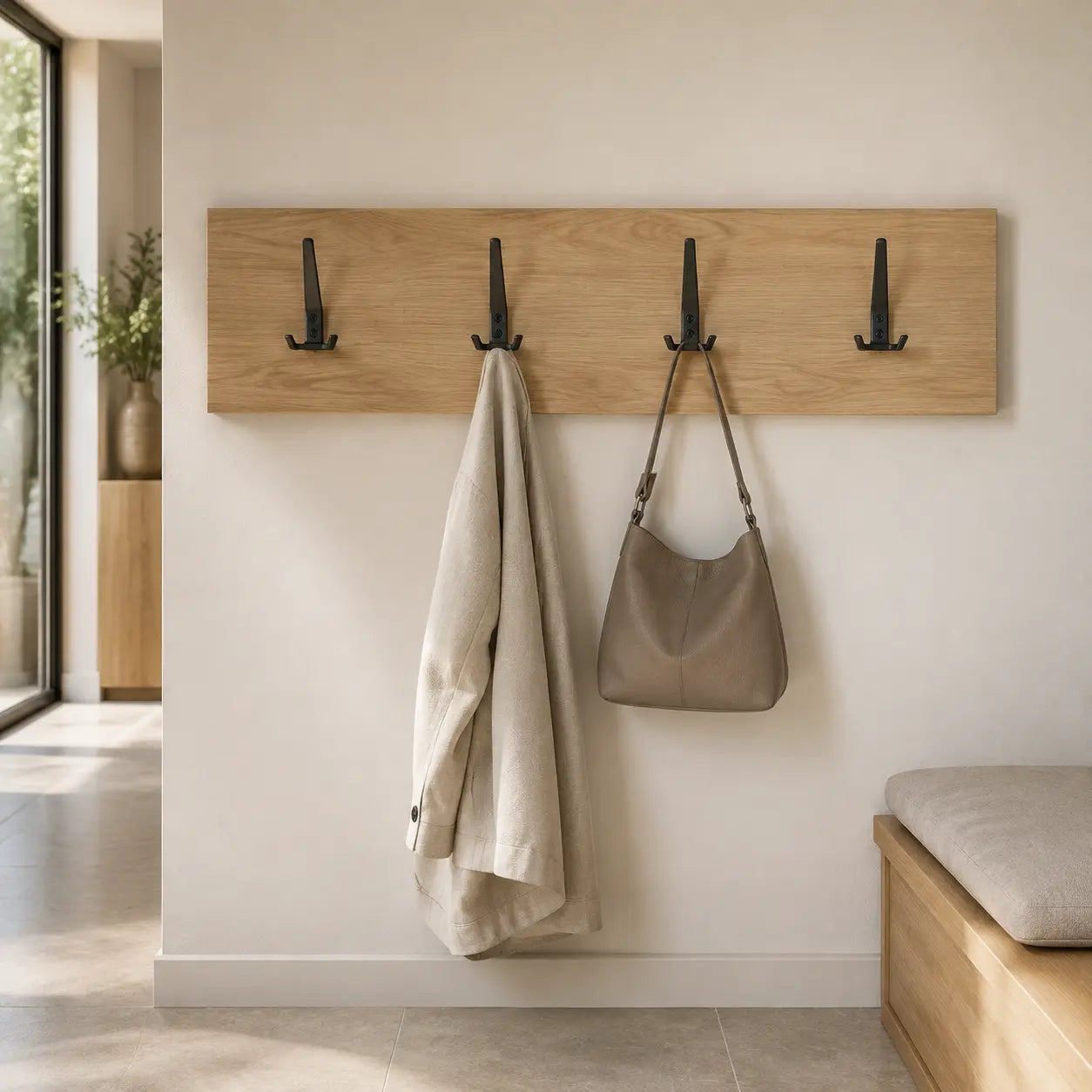Black wall-mounted coat rack with three hooks, STAALFABRIQ brand, designed for hanging coats and accessories.