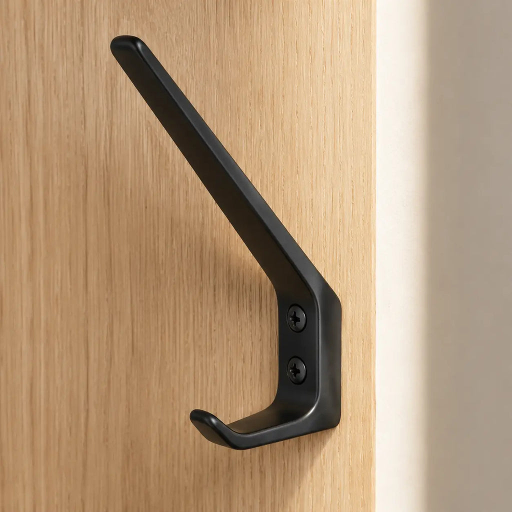 Black STAALFABRIQ wall hook with two hooks, mounted on a wall for hanging coats, bags, or accessories.