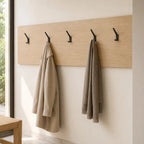 Black wall hook with two hooks from STAALFABRIQ, mounted on a wall, suitable for hanging coats, bags, or accessories.